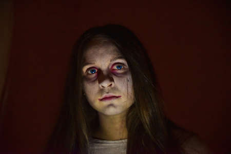 Portrait of a girl with scary makeup and bright blue lenses at a Halloween party. Make-up with your...