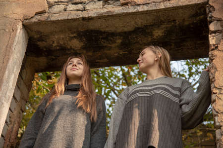 Two teenage girls in a dilapidated window opening of an old house.の写真素材