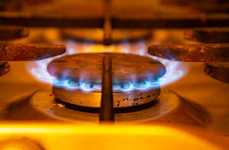 Burning blue flames gas. Focus on the front edge of the gas burners.