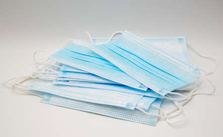 Blue medical protective masks are stacked on a white background.の写真素材
