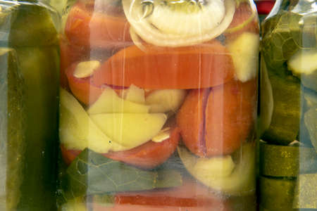 Full frame of a jar with pickles, cucumbers, peppers and tomatoes as a backdrop. Home-made preparations.の写真素材