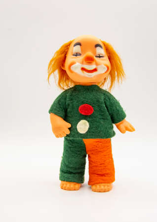 An old toy, a red-haired clown, in a bright suit on a white background.の写真素材