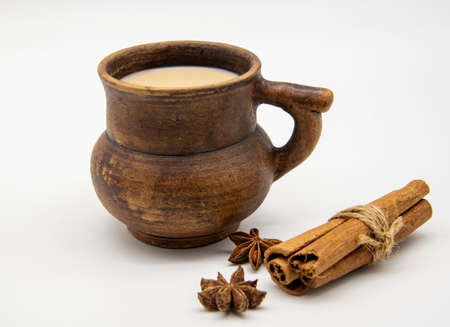 Brown clay mug with drink, cinnamon sticks and star anise on a white background.の写真素材