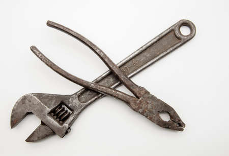 Old rusty pliers and an adjustable wrench on a white background.の写真素材