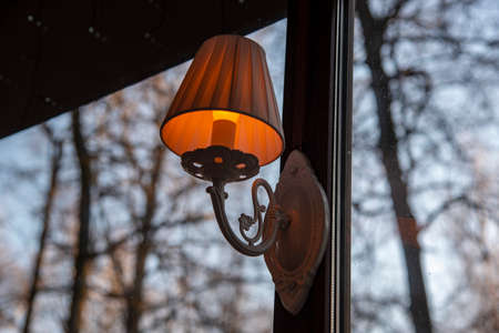 Burning vintage lamp on the window frame. Outside the window is an autumn Park.の写真素材