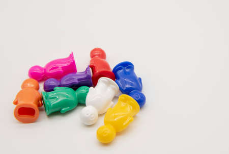 Board game colorful plastic figurines lie in a pile on a light background.