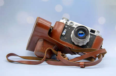 An old-fashioned camera with a leather case on a blue background.のeditorial素材