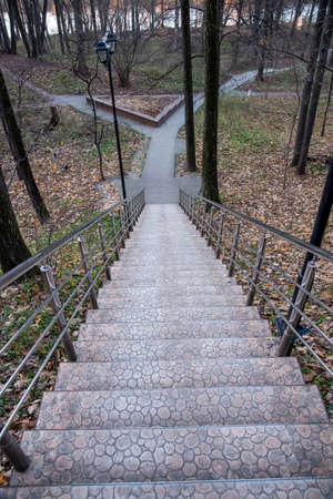 Long stone staircase with metal railing in autumn Park, top view.の写真素材