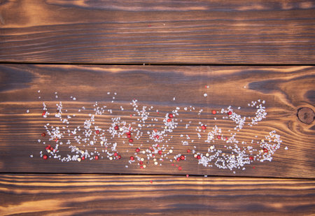 Void wooden background with wooden texture and scattered spices on it. Top view of a cutting Board sprinkled with salt and pepper.の写真素材