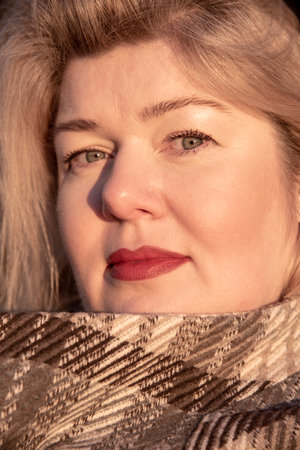 Portrait of a plump middle-aged woman with blonde hair and bright painted lips, illuminated by the sun.の写真素材