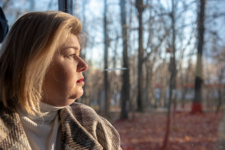 Portrait in profile of a plump blonde woman in a plaid coat by the window in a cafe.の写真素材