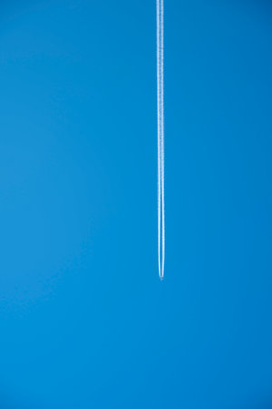 Airplane with white condensation tracks. Travel by airplane concept. Trails of exhaust gas from airplane engine. Aircraft with white stripes.の写真素材