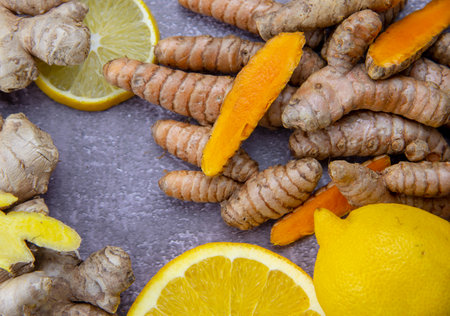Fresh turmeric root, ginger, oranges and lemon on a grey slate background. The concept of a healthy lifestyle, and food additives.の写真素材