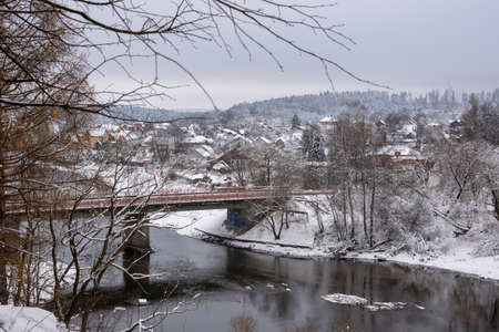 Winter rural landscape. A snow-covered village on the Bank of a river that is crossed by a road bridge.の写真素材