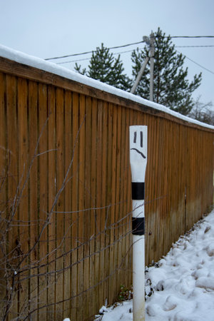 A limiting and warning column near the brown fence. A parody of a human face on a pole.の写真素材