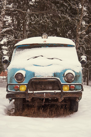 Russia, Moscow region, December 2020. An old rusty broken ambulance van stands in a snow-covered...