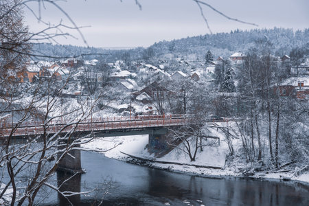 Winter rural landscape. A snow-covered village on the Bank of a river that is crossed by a road bridge.の写真素材