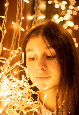 Portrait of a beautiful girl with a garland in her hands on a glowing background.