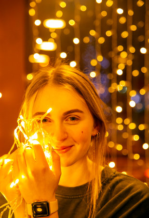 Portrait of a beautiful girl with a garland in her hands on a glowing background.の写真素材