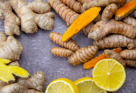 Fresh turmeric root, ginger, oranges and lemon on a grey slate background. The concept of a healthy...