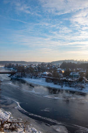 Winter frosty landscape. Frozen river, village covered with snow on the shore.の写真素材