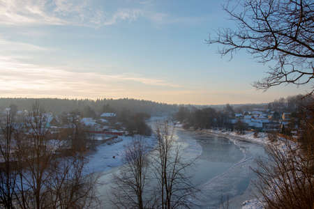 Winter frosty landscape. Frozen river, village covered with snow on the shore.の写真素材