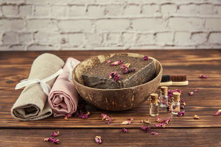 Organic aromatic handmade soap in a coconut bowl and personal care items made of natural materials on a wooden countertop. The concept of a healthy lifestyle.の写真素材