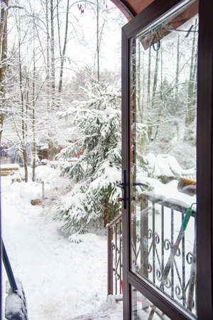 View of the snow-covered courtyard through the glass open door of the cottage.の写真素材