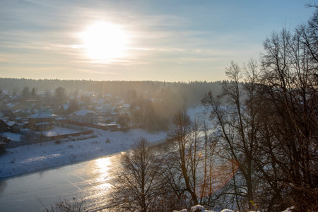 Winter frosty landscape. Frozen river, village covered with snow on the shore.の写真素材