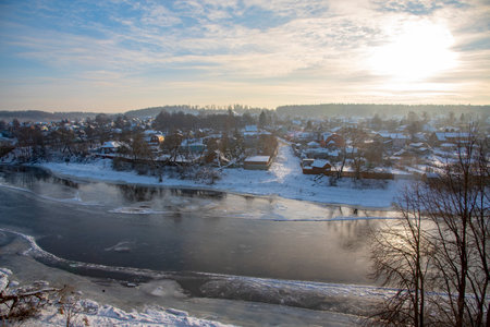 Winter frosty landscape. Frozen river, village covered with snow on the shore.の写真素材