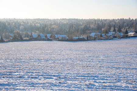 Winter frosty landscape. A snow-covered village on the edge of a wide field.の写真素材