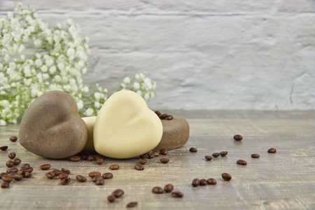 Fragrant coffee natural handmade soap in the shape of a heart and coffee beans on a wooden countertop.の写真素材