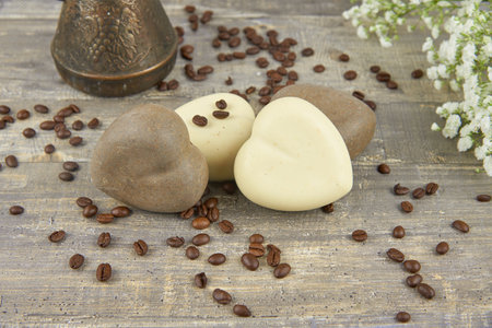 Fragrant coffee natural handmade soap in the shape of a heart and coffee beans on a wooden countertop.の写真素材