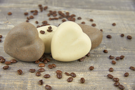 Fragrant coffee natural handmade soap in the shape of a heart and coffee beans on a wooden countertop.の写真素材