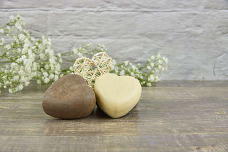 Handmade soap in the shape of a heart decorated with flowers on a wooden countertop. The concept of a healthy lifestyle. Product advertisingの写真素材
