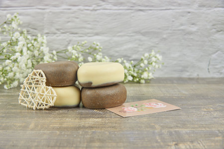 Handmade soap in the shape of a heart decorated with flowers on a wooden countertop. The concept of a healthy lifestyle. Product advertisingの写真素材