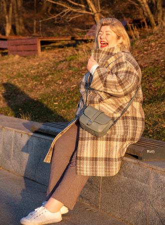 Portrait of a plump, middle-aged blonde woman walking in a park on a sunny late-autumn day.の写真素材