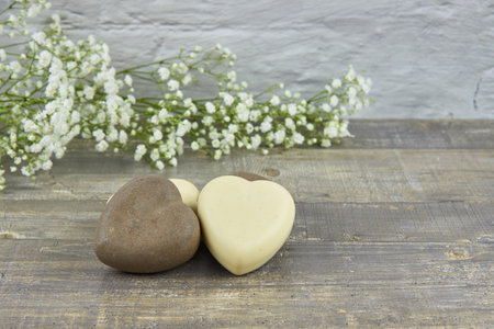 Handmade soap in the shape of a heart decorated with flowers on a wooden countertop. The concept of a healthy lifestyle. Product advertisingの写真素材