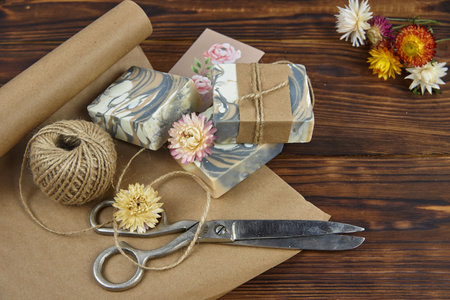 Fragrant colorful handmade soap, scissors and rope, lie on the packaging paper. Healthy lifestyle, online sales.の写真素材
