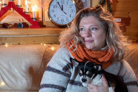 Portrait of a beautiful, plump, middle-aged blonde woman sitting on a sofa with a Chihuahua .の写真素材