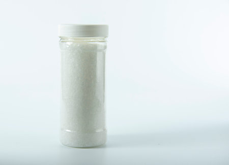 Transparent jar with coarse salt on a light background.の写真素材