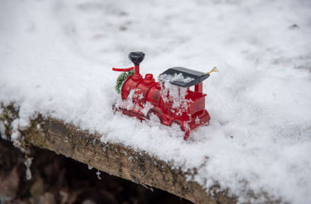 A small red toy train stands in the fluffy snow.の写真素材