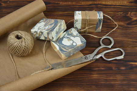 Fragrant colorful handmade soap, scissors and rope, lie on the packaging paper. Healthy lifestyle, online sales.の写真素材