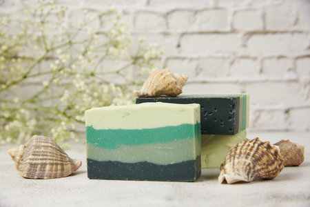 Fragrant striped handmade soap, seashells and stones on a light countertop against a brick wall. SPA product, healthy lifestyle.の写真素材