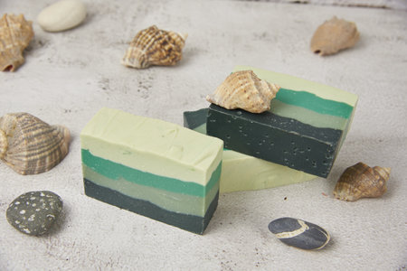 Fragrant striped handmade soap, seashells and stones on a light countertop. SPA product, healthy lifestyle.の写真素材