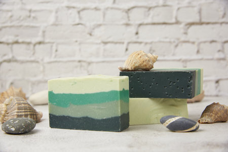 Fragrant striped handmade soap , seashells and stones on a light countertop against a brick wall. SPA product, healthy lifestyle.の写真素材