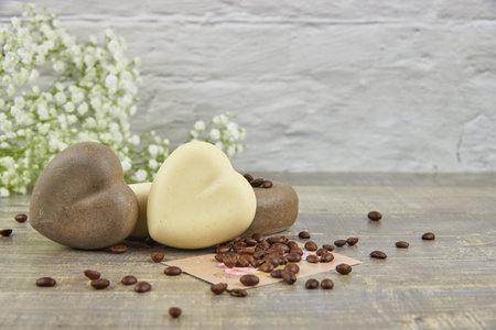 Fragrant coffee natural handmade soap in the shape of a heart and coffee beans on a wooden countertop.の写真素材