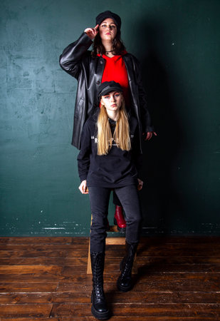 Two charming teenage girls with bright makeup, dressed in a grunge style, against a dark wall, a photo shoot in the studio. Youth trend.の写真素材