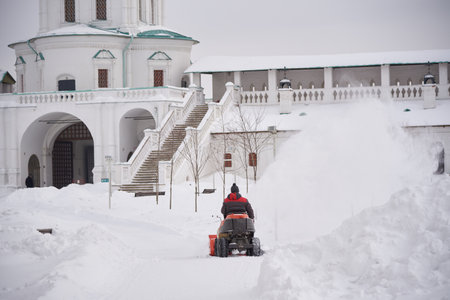 Russia, Moscow region, February 2021.A warmly dressed man on a snow plow removes snow on the territory of the monastery on a frosty day.のeditorial素材