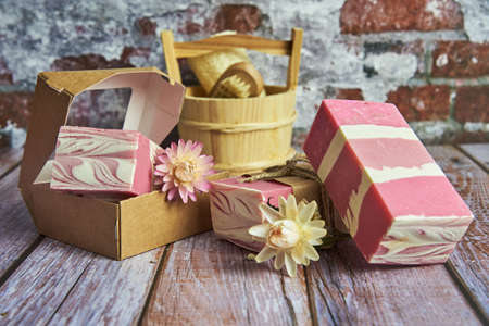 Fragrant pink organic handmade soap and other personal care items on the wooden countertop. Healthy...